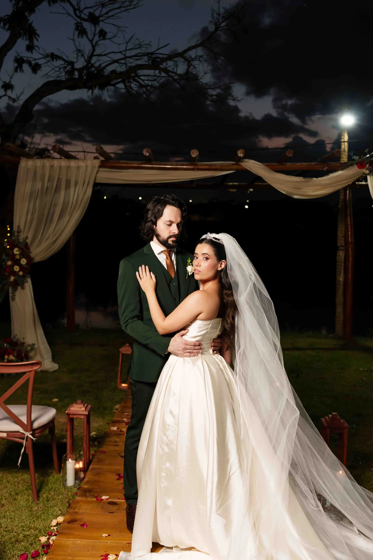 Gabriela e Raphael abraçados no jardim à noite