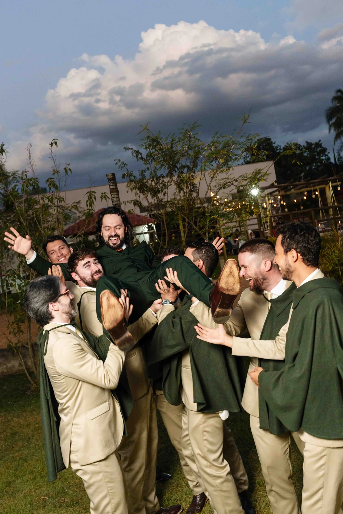 Rapha com terno verde e os padrinhos com trajes claros e gravatas champagne, celebrando juntos